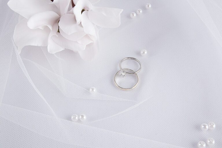 Chic wedding background. Two platinum engagement rings, a diamond ring on a white bridal veil